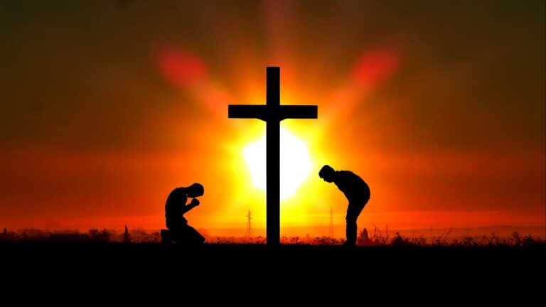 Two people kneeling at a cross during sunset – symbol of faith, hope, and Christian devotion
