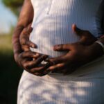 photo of pregnant woman with her hands and her husbands hands on her pregnant stomach... childless women are NOT more blessed than women who bare God's children